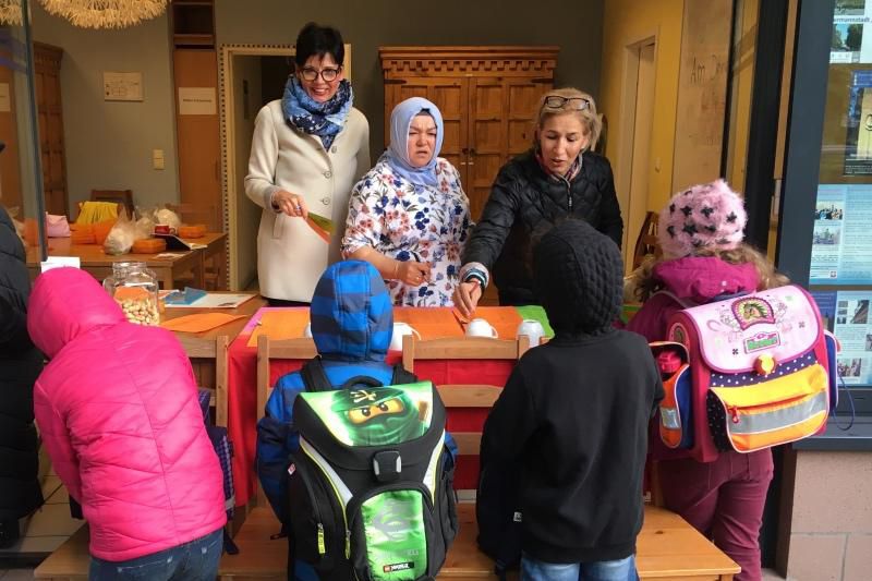 Erwachsene verteilen Brötchen an Kinder.