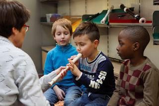 Lehrer bringt Kind bei, wie man Flöte spielt.