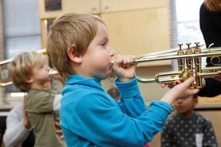 Kind spielt auf einer Trompete.