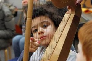 Kind spielt auf der Harfe.