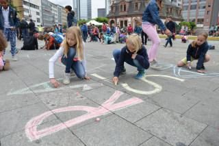 Kinder malen mit Kreide auf die Straße.