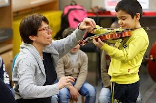 Musiklehrer bringt einem kleinen Jungen bei, wie man Geige spielt.