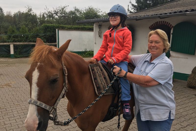 Kind reitet auf einem Pferd.