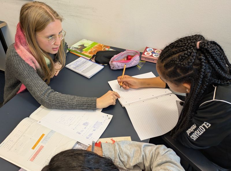 Eine Studentin hilft einem Mädchen beim Hausaufgaben machen