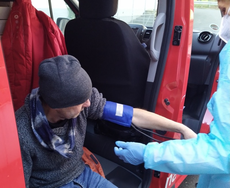 Ein Mann sitzt in einem Auto und wird von einem Arzt untersucht.