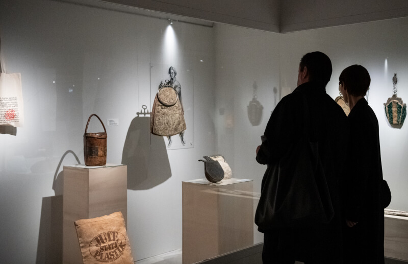 Zwei Personen betrachten eine Vitrine mit historischen Taschen und ledernen Alltagsobjekten im Deutschen Ledermuseum Offenbach.